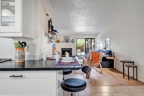 Une cuisine moderne avec des meubles blancs, un plan de travail noir et un coin repas comprenant une table ronde et des chaises.