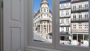 A view through a window of a street with historic buildings, a 'FLYING TIGER' shop, and a 'LONDON' sign.