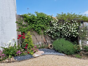 A garden with a variety of plants, a stone wall, and a gravel path. - House with a fenced-in yard, a 5-minute walk from the beach, next to the forest   (La Barre-de-Monts)