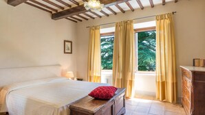 Un dormitorio con cama, mesita de noche, cómoda y ventana con cortinas.