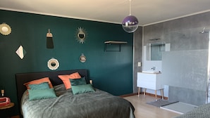 Un dormitorio moderno con cama, mesita de noche, cómoda y zona de ducha.
