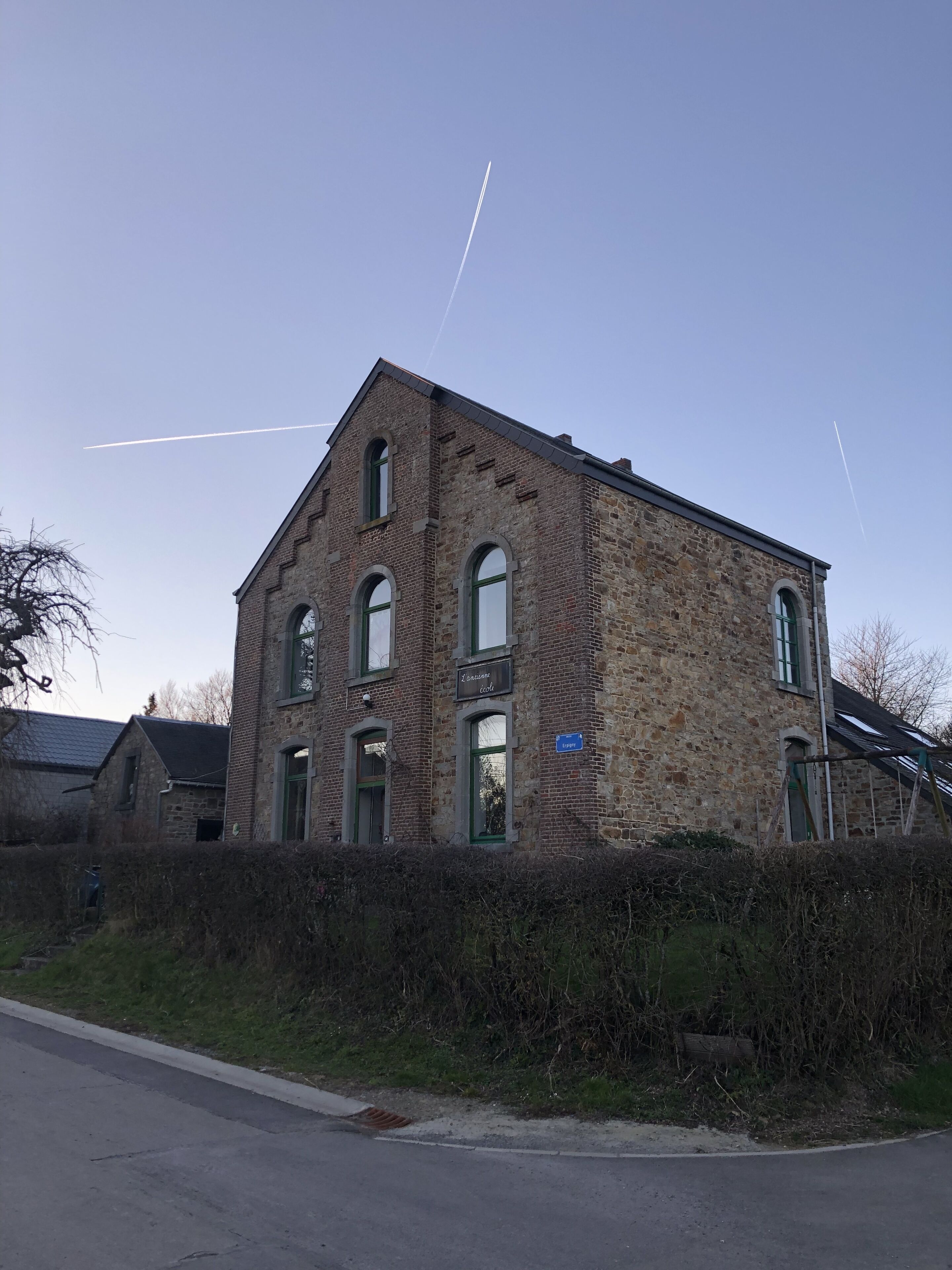 A large, historic stone building with multiple windows and a sign indicating it is a school.
