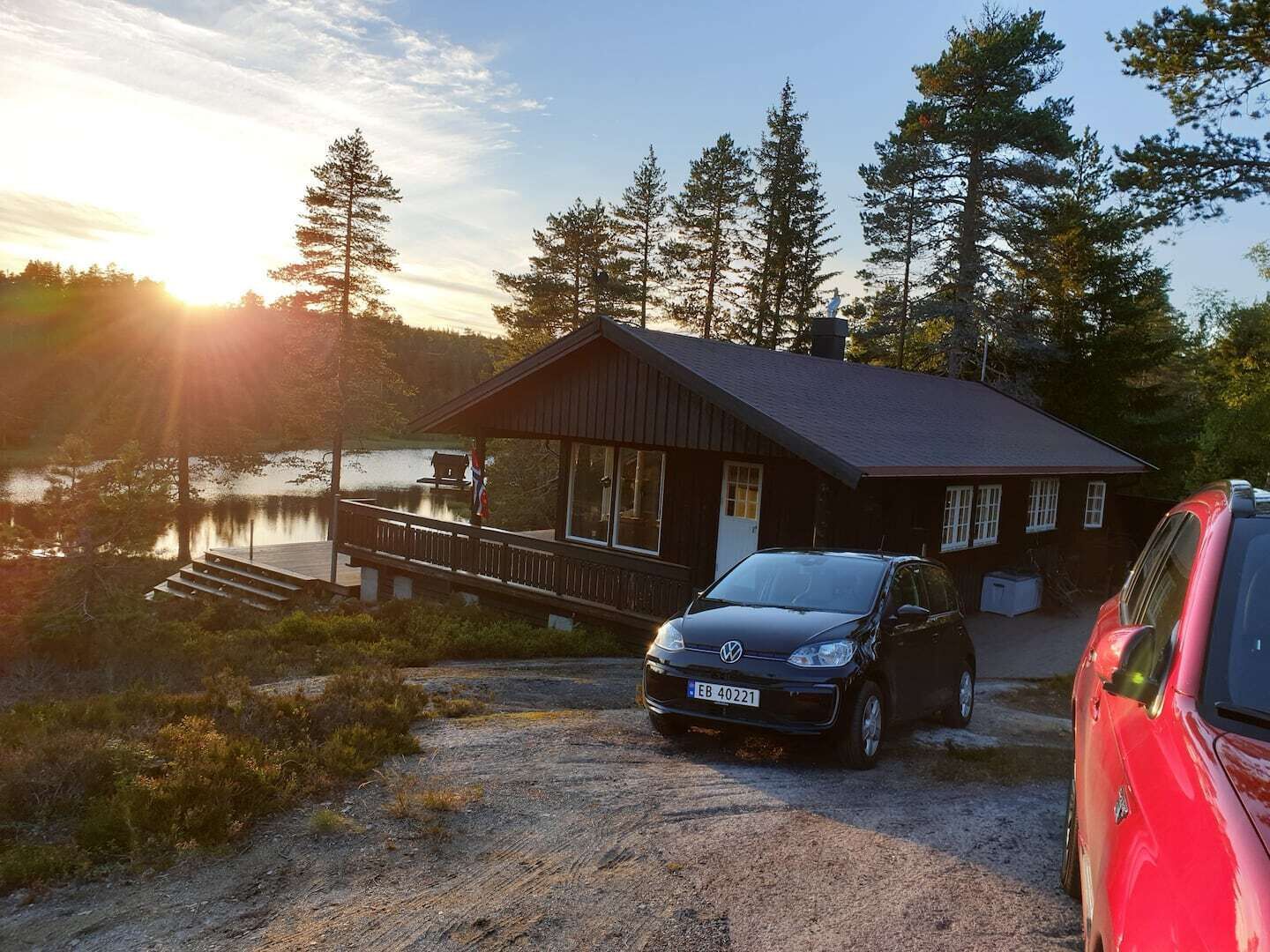 A cabin with a dock extending into a lake, surrounded by trees.