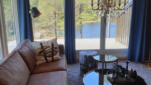 Un salon avec une grande fenêtre, un lustre, un canapé et une table basse.