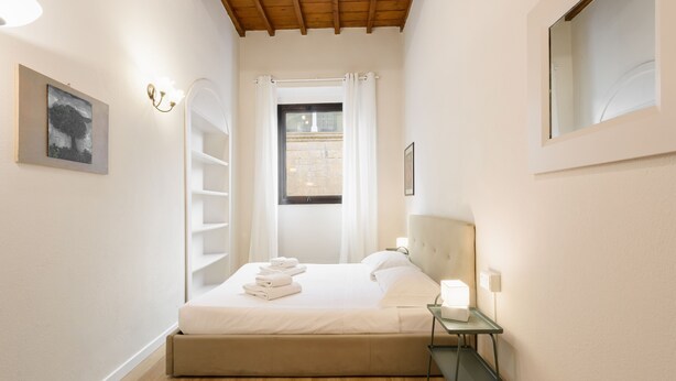 Ein Schlafzimmer mit Bett, Nachttisch und einem Vorhangfenster.