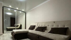 A modern living room with a sectional sofa, a large mirror, and a wooden floor. - Daniko (Taraz)
