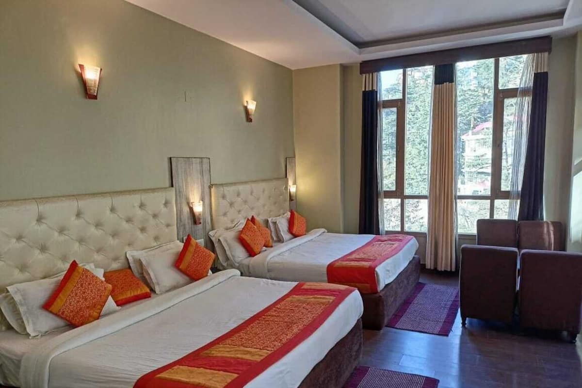A hotel room with two beds, a sofa, and a large window with curtains.