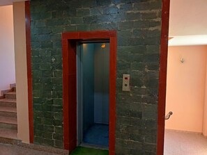An elevator with a red frame and a stone wall. - The Grand Madhushala Shimla (Shimla)