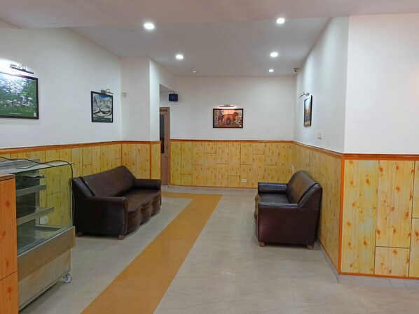 A reception area with two leather sofas, a reception desk, and a wooden panel wall. - The Grand Madhushala Shimla (Shimla)