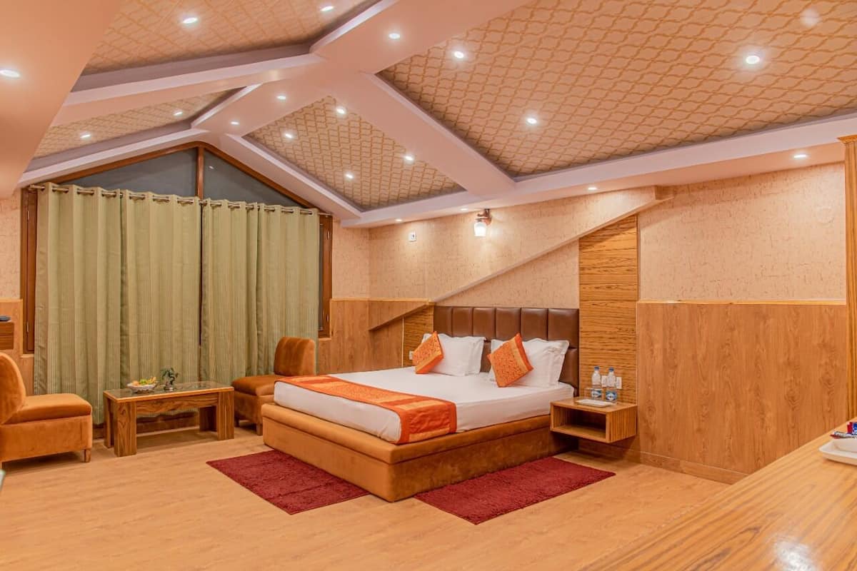A modern hotel room with a large bed, wooden furniture, a small table, and a red rug.