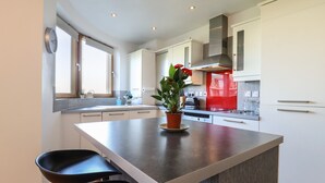 Una cucina moderna con isola centrale, mobili bianchi e una parete di sfondo rossa.