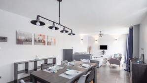 A modern dining area with a long table, chairs, and a ceiling light fixture.