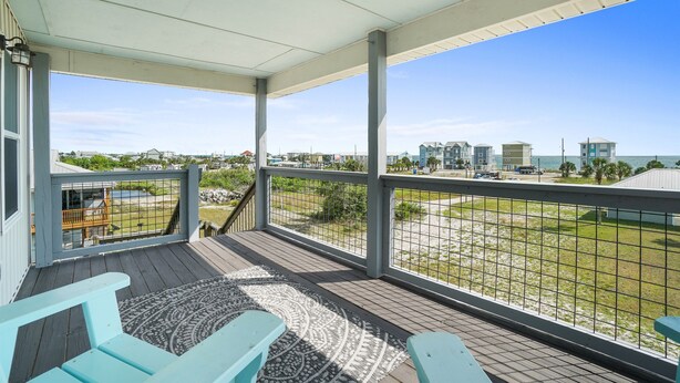 Überdachte Terrasse mit Blick auf Strand und Häuser.