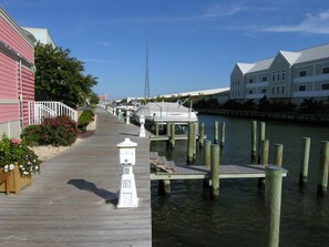 A wooden boardwalk leading to a dock with a white lighthouse-style structure marked '97'. - Bright, modern 3-bedroom luxury condo in gated community, free WiFi, private bayside beaches, an indoor and outdoor pool, and more located midtown and a couple blocks to the ocean! (Ocean City)