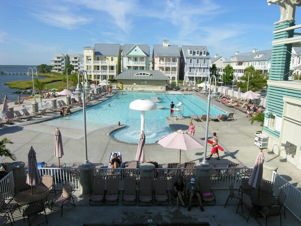 A resort pool area with lounge chairs, umbrellas, and a view of the ocean.
