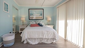 Um quarto com uma cama grande, duas mesas de cabeceira com luminárias, um quadro na parede, uma janela com persianas e um ventilador de teto.