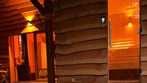 A hot tub with a control panel, wooden walls, and a door.
