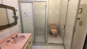 Ein kleines Badezimmer mit einem rosa Waschbecken, einer Toilette und einer Duschkabine aus Glas.