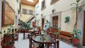 A spacious indoor area with multiple wooden tables and chairs, a staircase, and various potted plants. - OYO Posada Santa Cecilia, Jerez Zacatecas  (Jerez de Garcia Salinas)