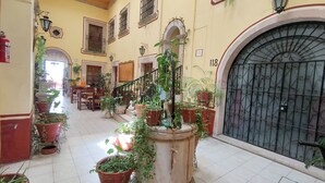 A corridor with potted plants, a staircase, and a large black gate. - OYO Posada Santa Cecilia, Jerez Zacatecas  (Jerez de Garcia Salinas)