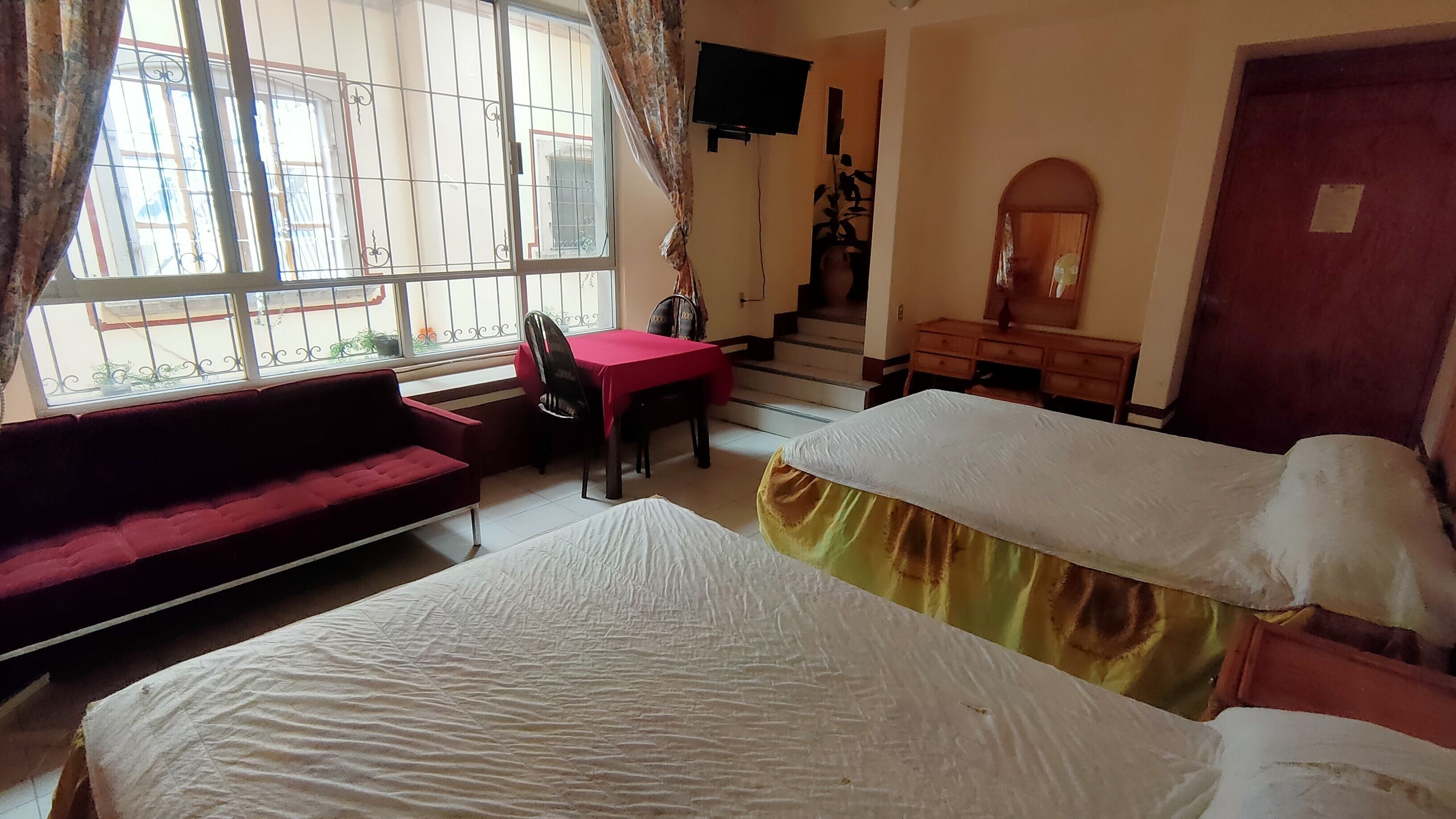A room with a bed, a sofa, a desk, and a TV.