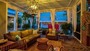 Un patio intérieur accueillant, avec des meubles en osier, une table ronde au centre et des plantes en pot.
