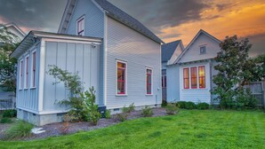 Une maison à deux étages avec un toit en pente, un petit garage attenant et une pelouse bien entretenue.
