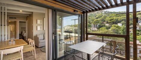 A modern outdoor dining area with a wooden deck, a table, and chairs.