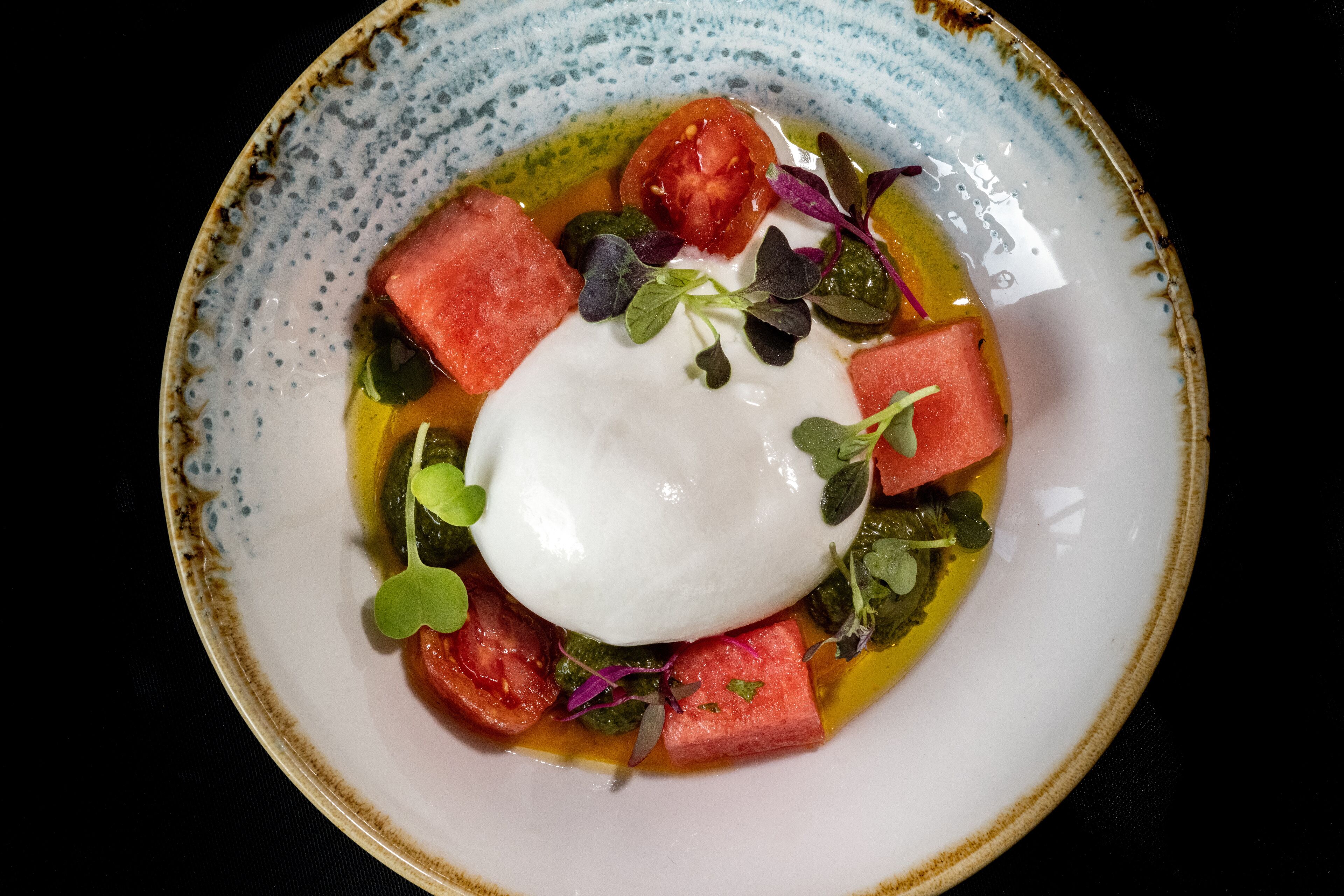 A bowl of food with a poached egg, tomatoes, and greens.
