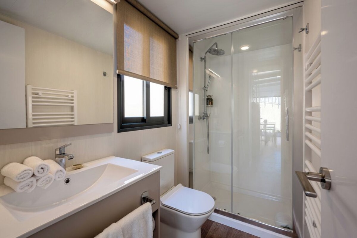 A modern bathroom with a glass-enclosed shower, a white sink, and a toilet.