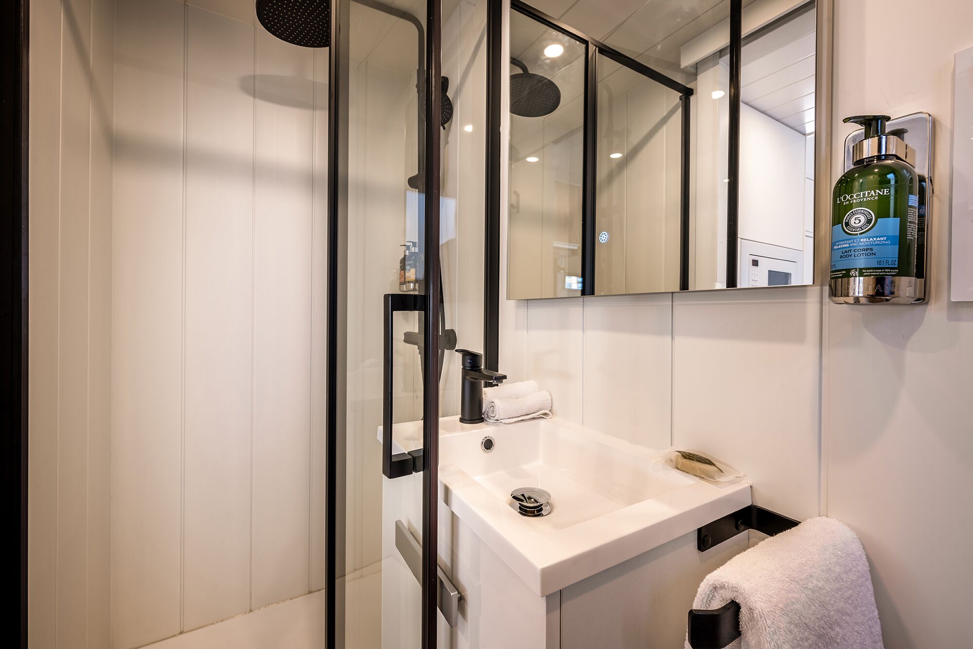 Un bagno moderno con cabina doccia in vetro, lavandino bianco e specchio.