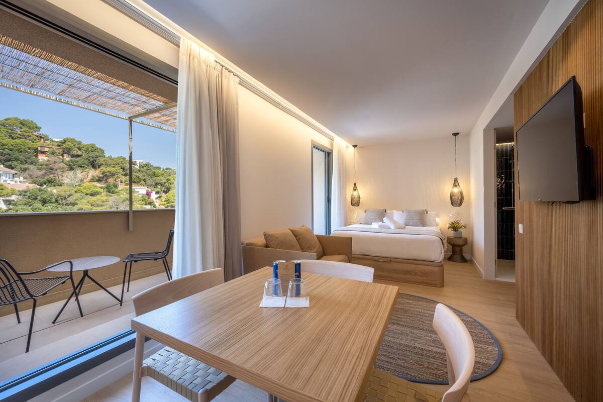 Une chambre d’hôtel moderne dotée d’un balcon, d’un lit, d’une télévision et d’un coin repas.