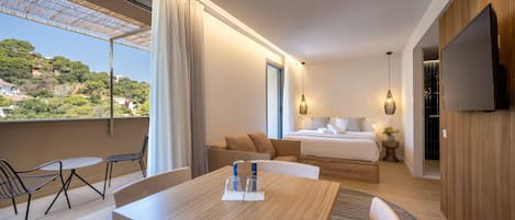 Una habitación de hotel moderna con balcón, cama, televisor y zona de comedor.