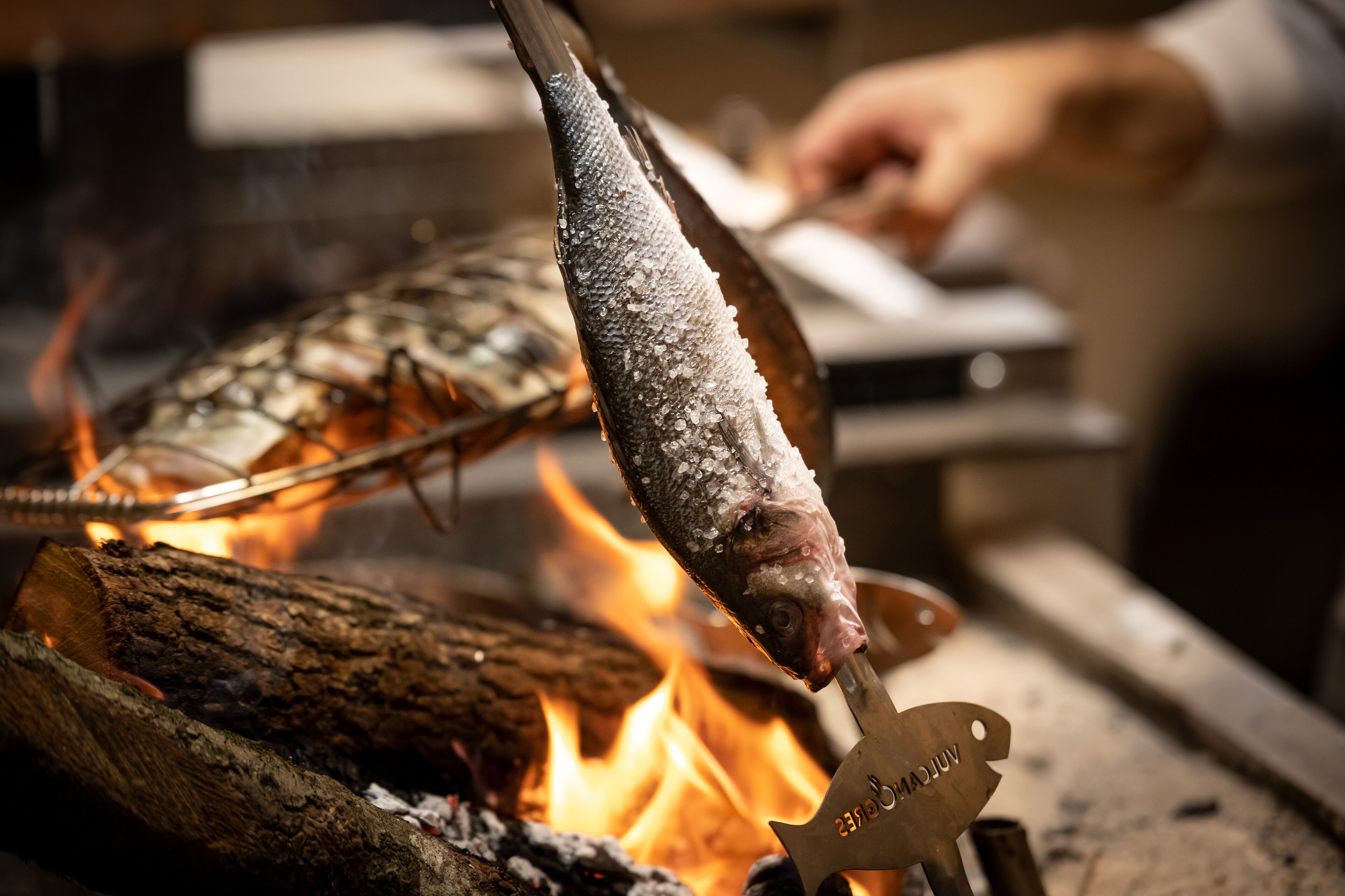 A fish being grilled over an open flame.