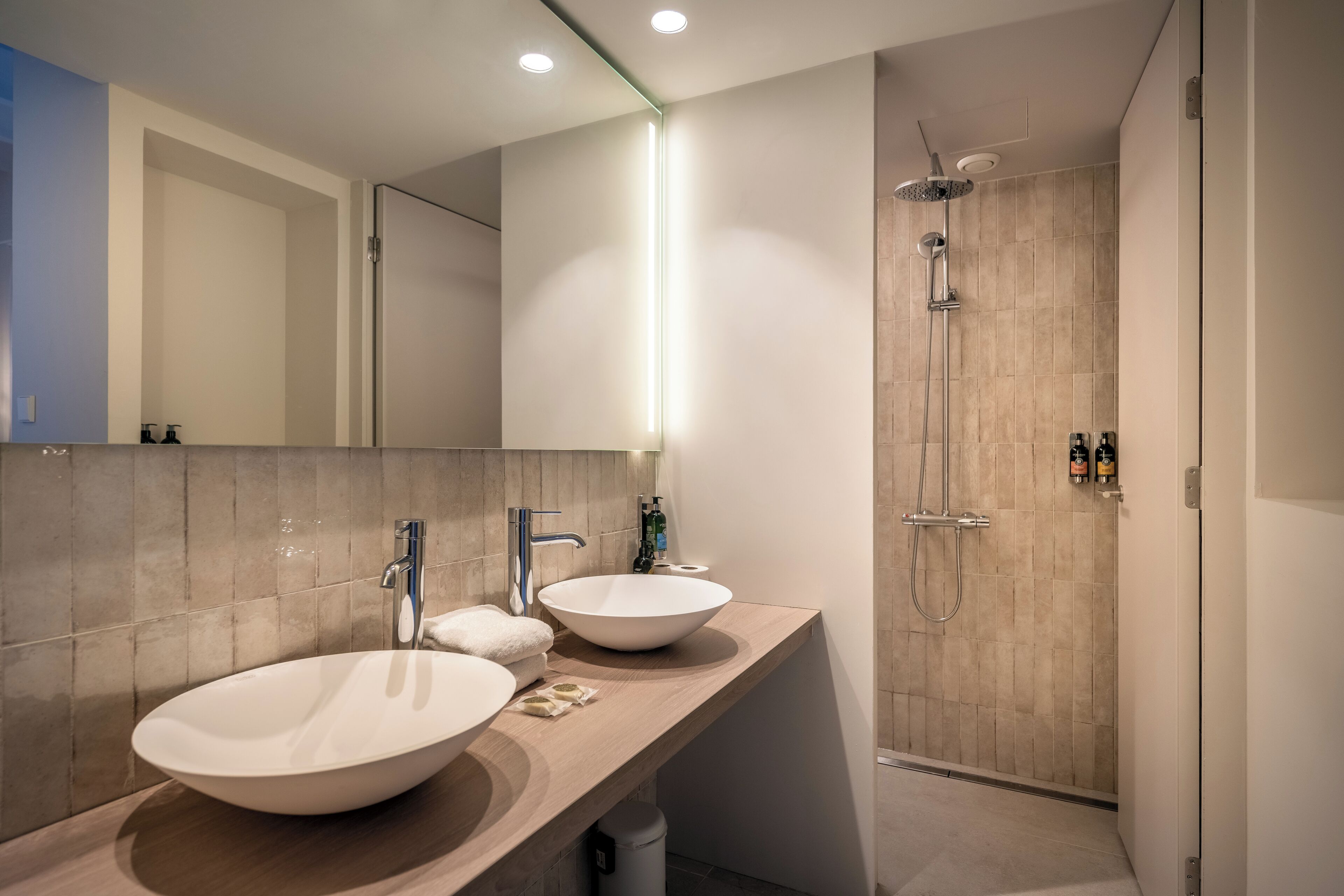 A modern bathroom with two large sinks, a shower, and a mirror.