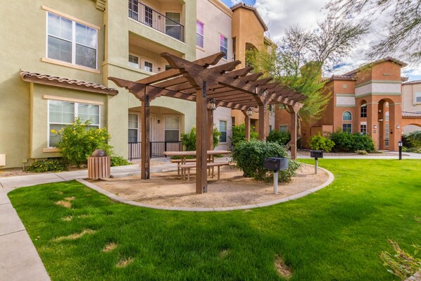 A courtyard with a wooden pergola, outdoor seating, and a well-maintained lawn.