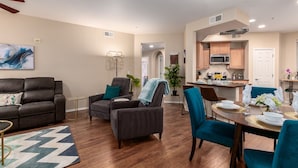 A modern living room with a sofa, armchairs, and a dining area with a table set for two. - Surprise Ground Floor Condo with 2 Private Courtyards! Heated Community Pool! (Surprise)
