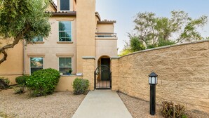 A residential building with a concrete pathway leading to a gated entrance. - Surprise Ground Floor Condo with 2 Private Courtyards! Heated Community Pool! (Surprise)