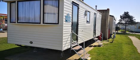 A mobile home with a front porch, a door, and a window.