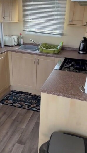 A compact kitchen with a sink, a green dish rack, a toaster, and a kettle. - Seaside Haven Retreat in Walton (Walton on the Naze)