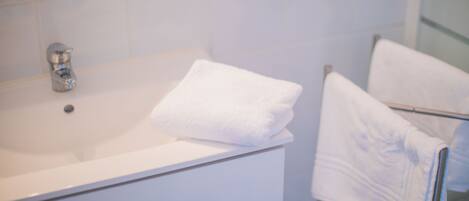 Un baño con un lavabo blanco, una toalla en el mostrador y un perchero.