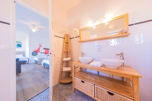 Un baño moderno con tocador de madera, dos lavamanos, un espejo y un ventilador de techo.