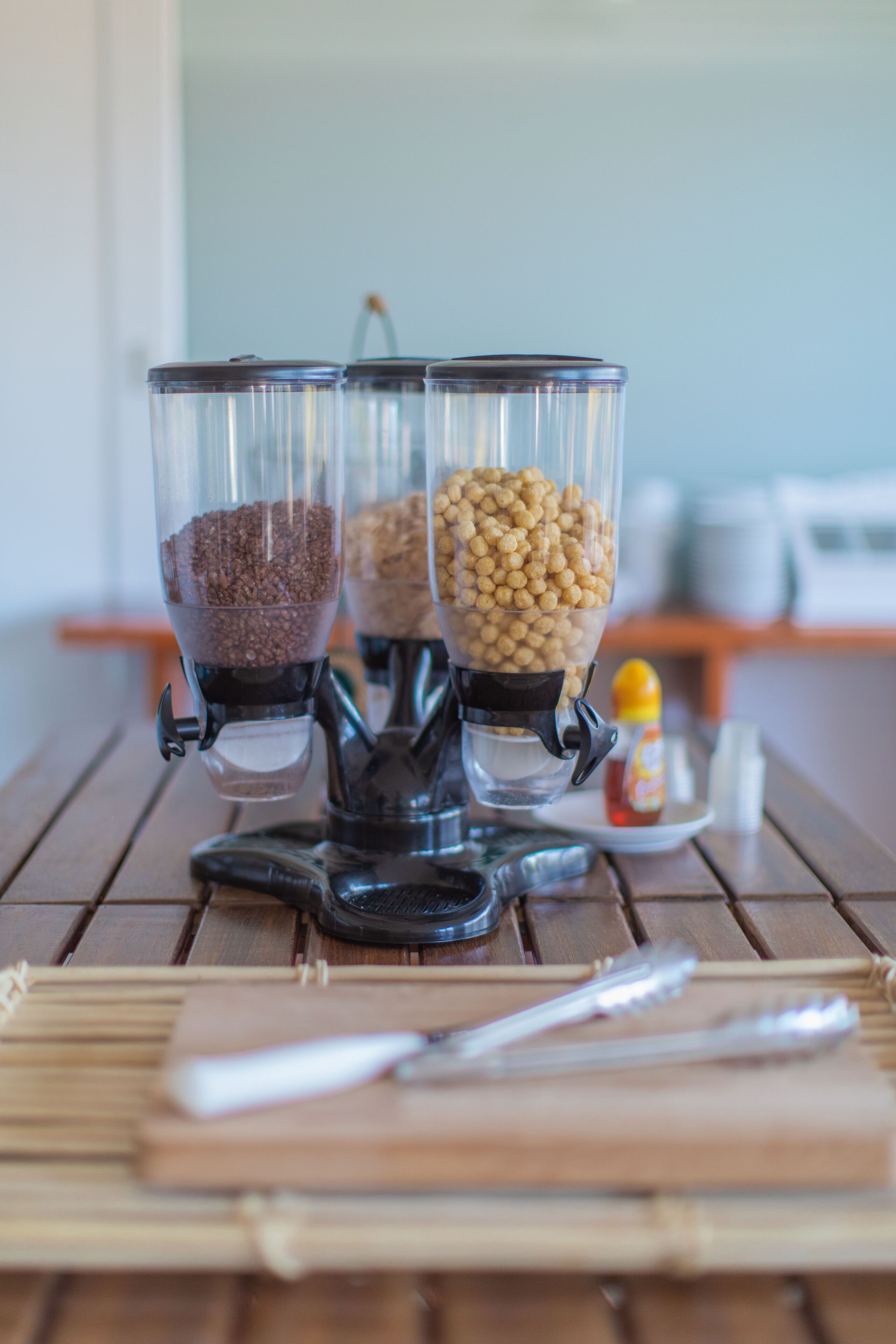 A coffee grinder with three containers of coffee beans on a wooden table.