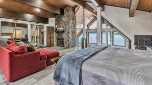 Un espacio habitable amplio con chimenea de piedra, un sof á rojo y una cama grande.
