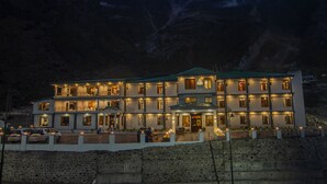 A multi-story hotel with a balcony, located near mountains. - Amritara The Avadh (Joshimath)