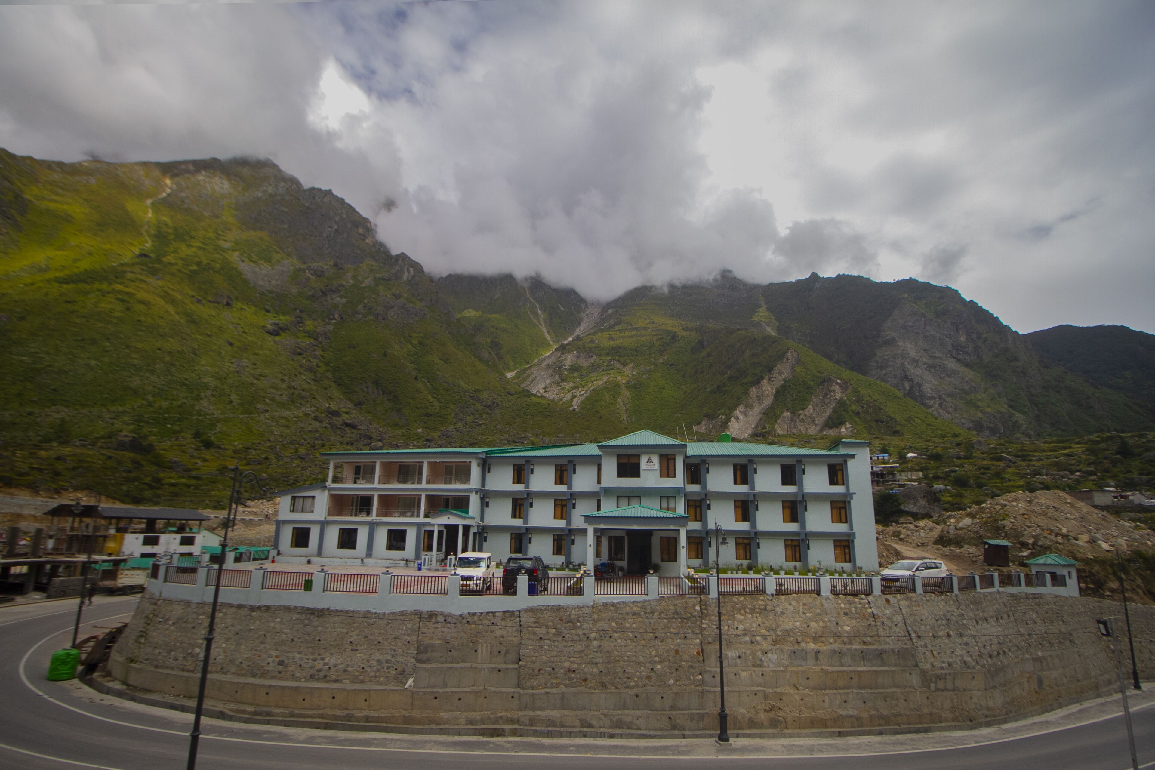 A multi-story hotel with a green roof, situated at the base of a mountain.