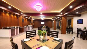 A dining area with a long table, chairs, and a chandelier. - Amritara The Avadh (Joshimath)