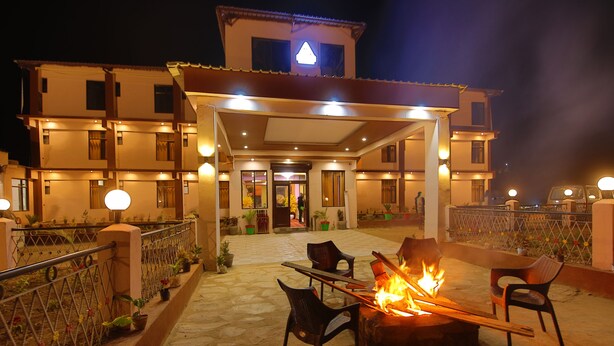 A hotel patio with a fire feature, outdoor seating, and a covered entrance. - Amritara The Avadh (Joshimath)