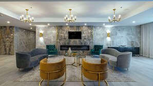 A modern living room with a fireplace, two sofas, a coffee table, and a TV mounted on the wall. - Halifax Tower Hotel & Conference Centre, an Ascend Collection Hotel (Halifax)