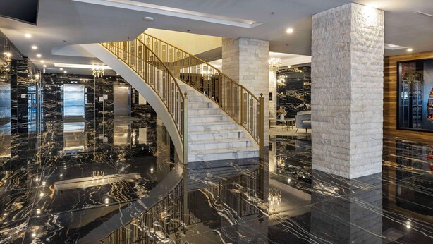 A modern lobby with a marble floor, a staircase with golden railings, and a stone pillar. - Halifax Tower Hotel & Conference Centre, an Ascend Collection Hotel (Halifax)